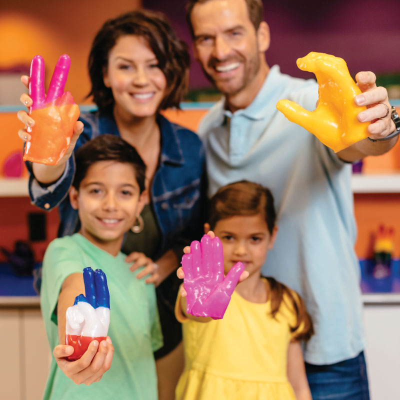 Family holding out colorful wax hands souvenirs